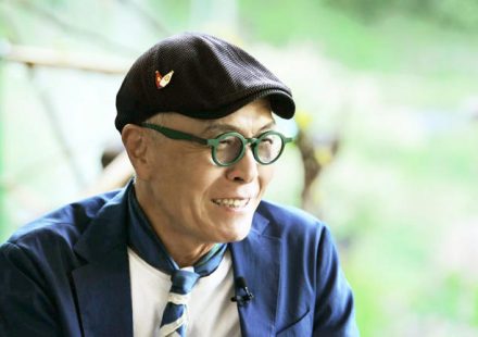 Host and legendary cartoonist Huh Young Man smiling warmly during a shoot for his food travel program.