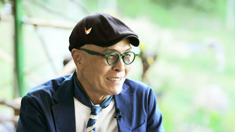 Host and legendary cartoonist Huh Young Man smiling warmly during a shoot for his food travel program.