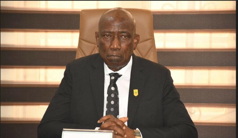 DIG Johnson Kokumo speaking at a press briefing in front of intercepted automatic rifles.