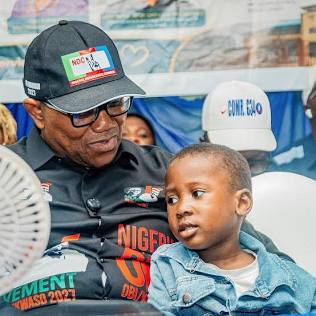 Peter Obi sitting alongside a young child during the medical outreach celebrating his 65th birthday.